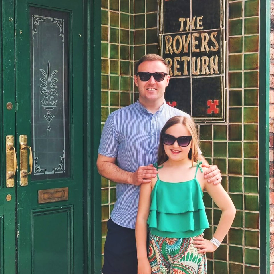 A man and his daughter pose proudly in front of The Rovers Return sign.