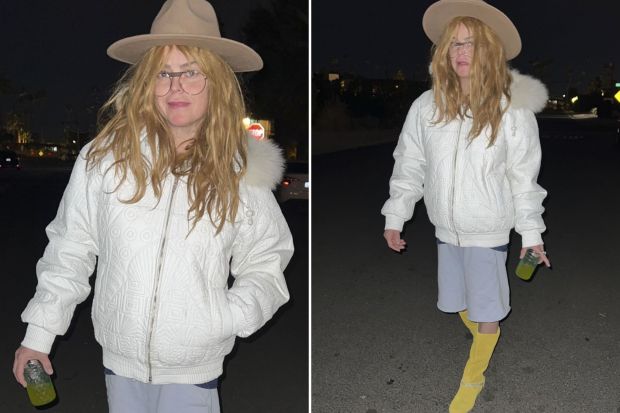 Woman in white jacket and hat walking at night.