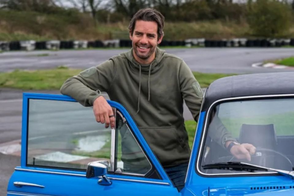 Man leaning on a blue classic car.