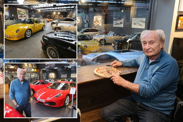 Man eating pizza in front of a classic car showroom.