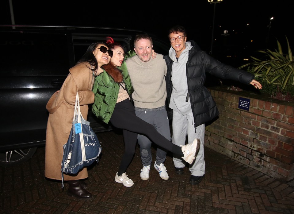 Four people posing for a photo outside a hotel.