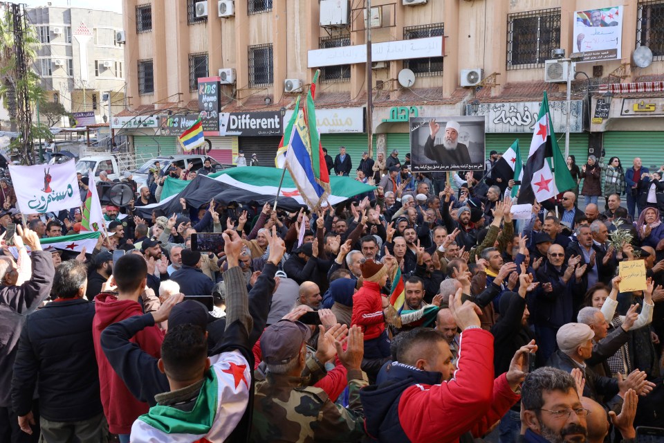 People chant slogans and wave the opposition flag during a gathering against the Syrian government