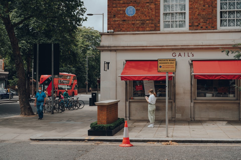 People wearing face masks walk past Gail's bakery in London.