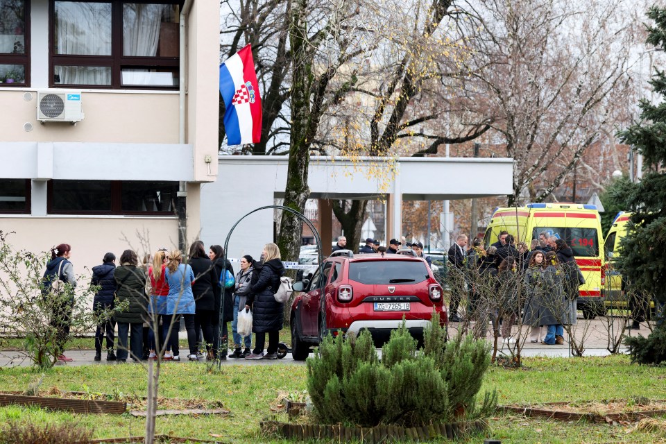 People gather outside a primary school near an ambulance after a knife attack.