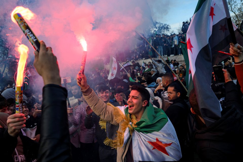 People wave Syrian opposition flags and hold flares in Istanbul on Sunday