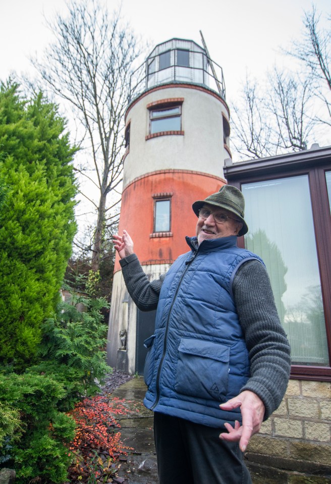 Man standing in front of his lighthouse-shaped house.