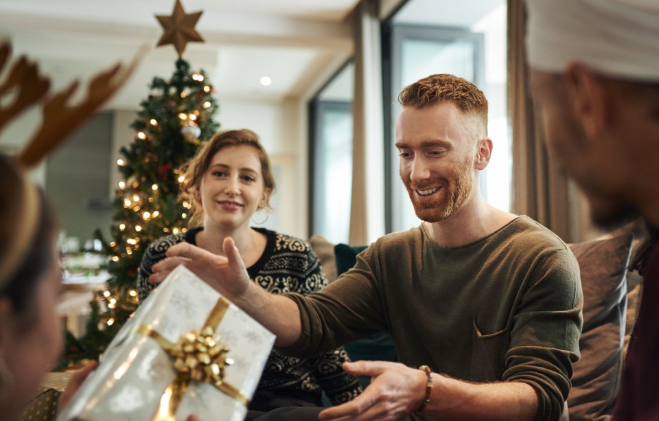 Shot of young friends opening their Christmas gifts together at home