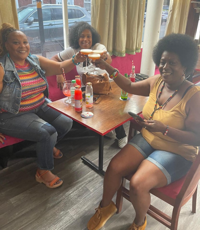 Three women toasting with cocktails at a pub.