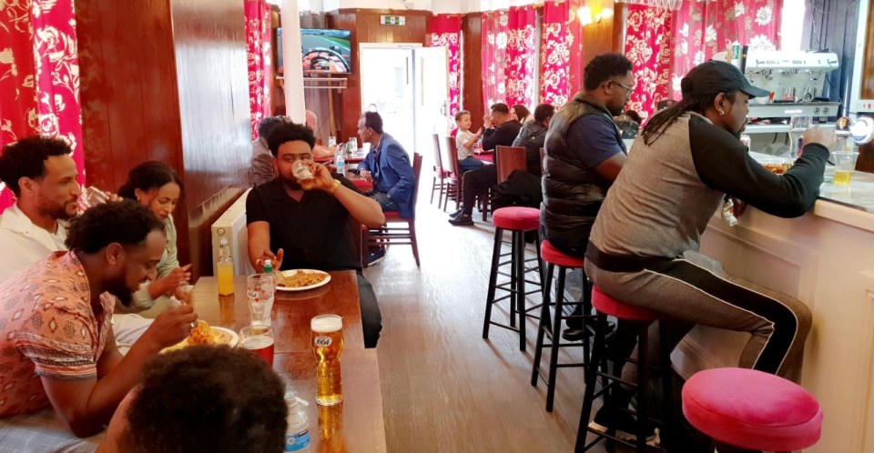 Patrons enjoying drinks and food at a pub.