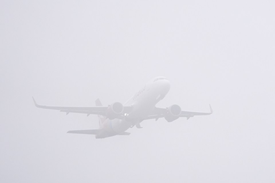 A plane takes off through thick fog at Gatwick yesterday