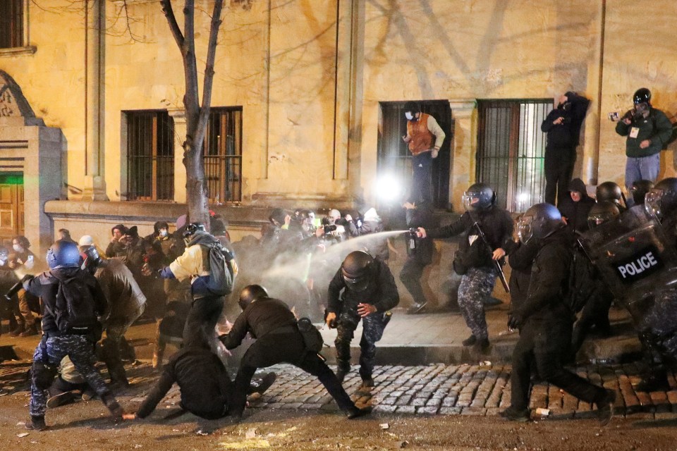 A police officer uses a crowd control spray against protesters