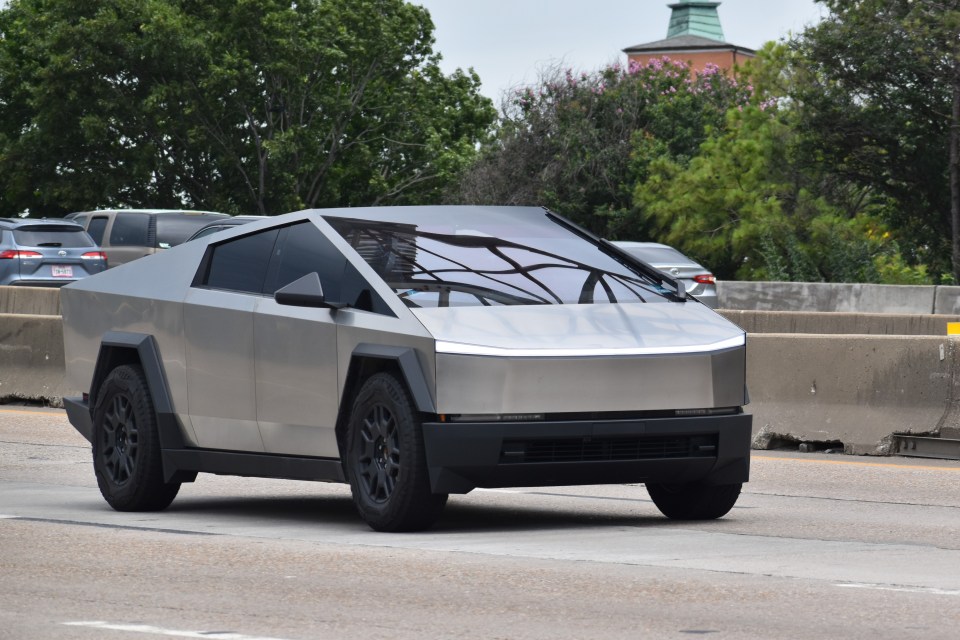 Silver Tesla Cybertruck driving on a highway.