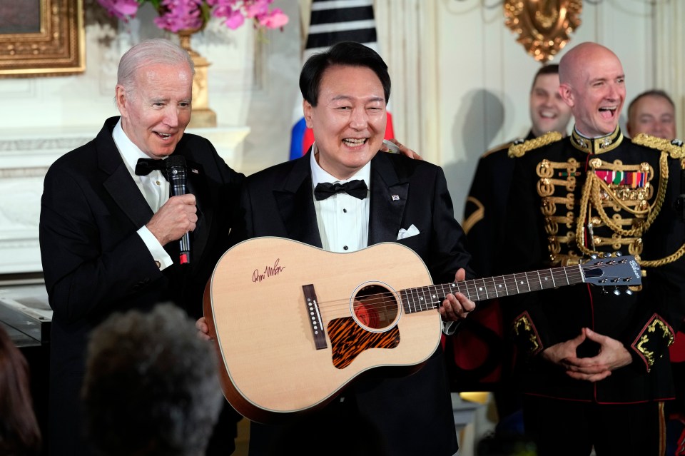 President Joe Biden surprises South Korea’s President Yoon Suk Yeol with a guitar signed by Don McLean in the State Dining Room of the White House