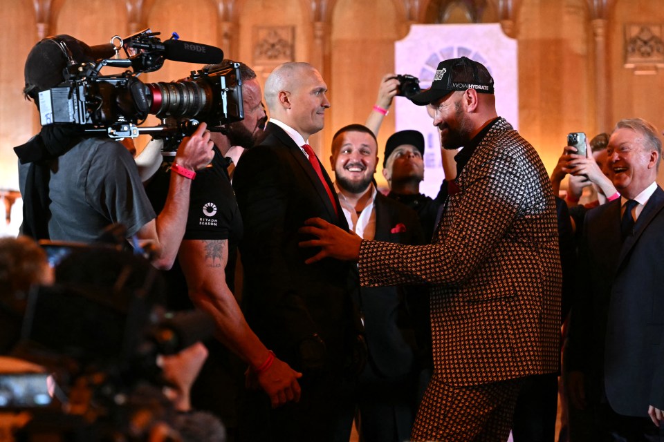 Tyson Fury tickles Oleksandr Usyk at a press conference.