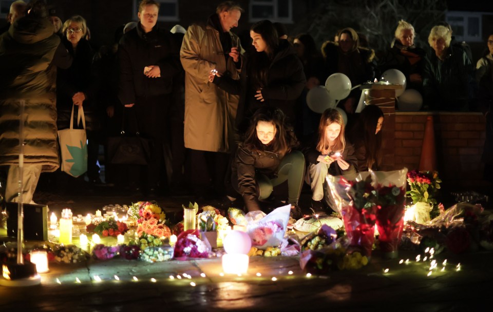 Vigil with candles and flowers outside a house where a murder occurred.