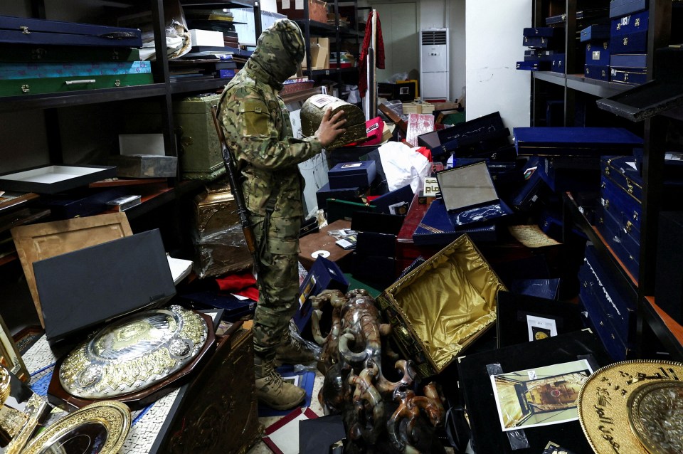 A rebel fighter holds and looks at personal souvenirs of Assad