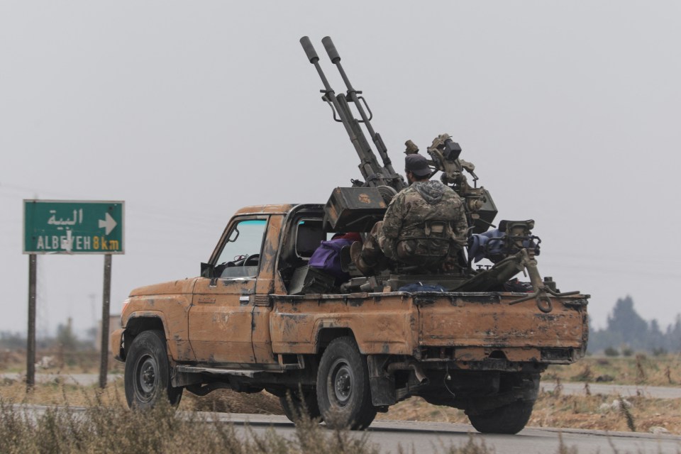 A rebel fighter sits on the back of a vehicle in Homs