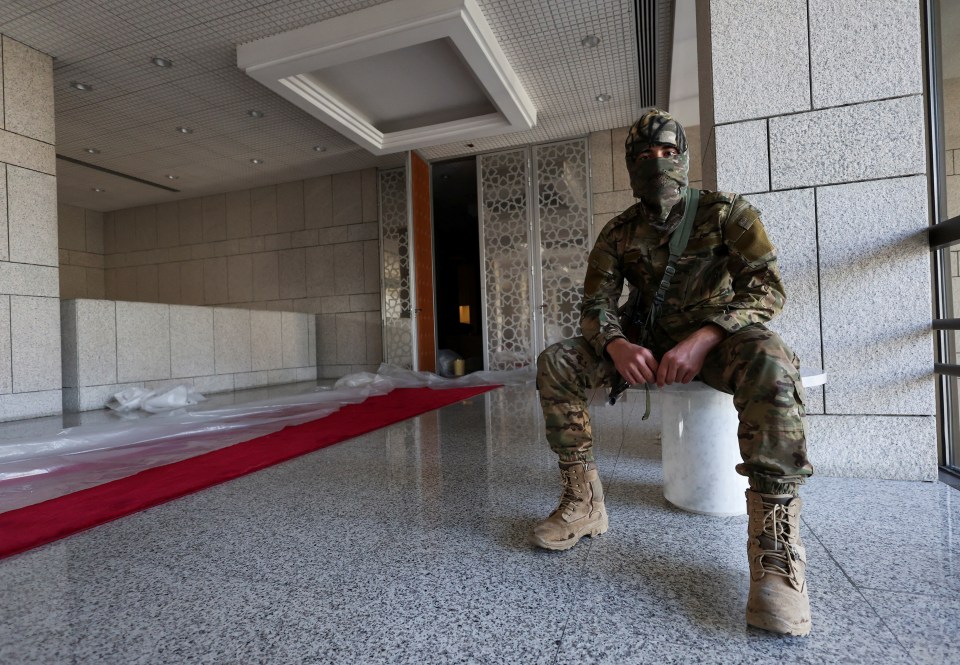 A rebel fighter sits at the entry hall in the Presidential Palace