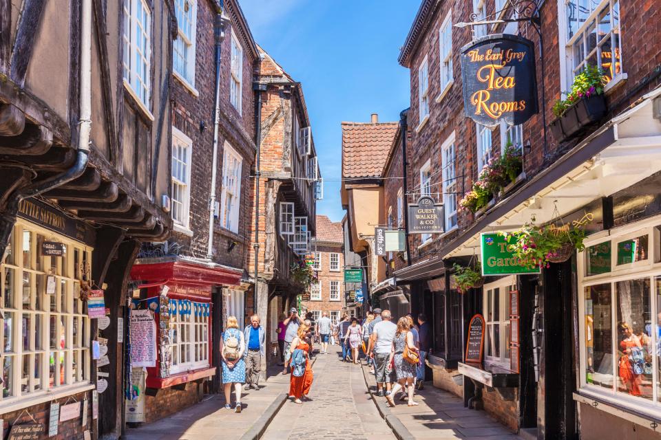 Tourists walking down a narrow, historic street in York, England.