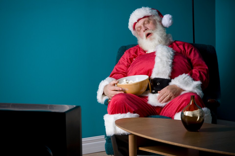 Santa Claus asleep in a chair with a bowl of popcorn.