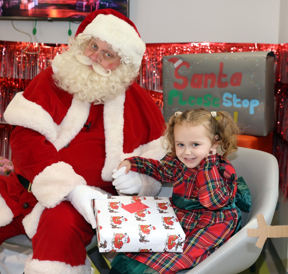 Santa Claus gives a gift to a young girl at a hospital.