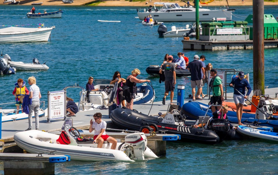 People launching and retrieving small motorboats at a marina.