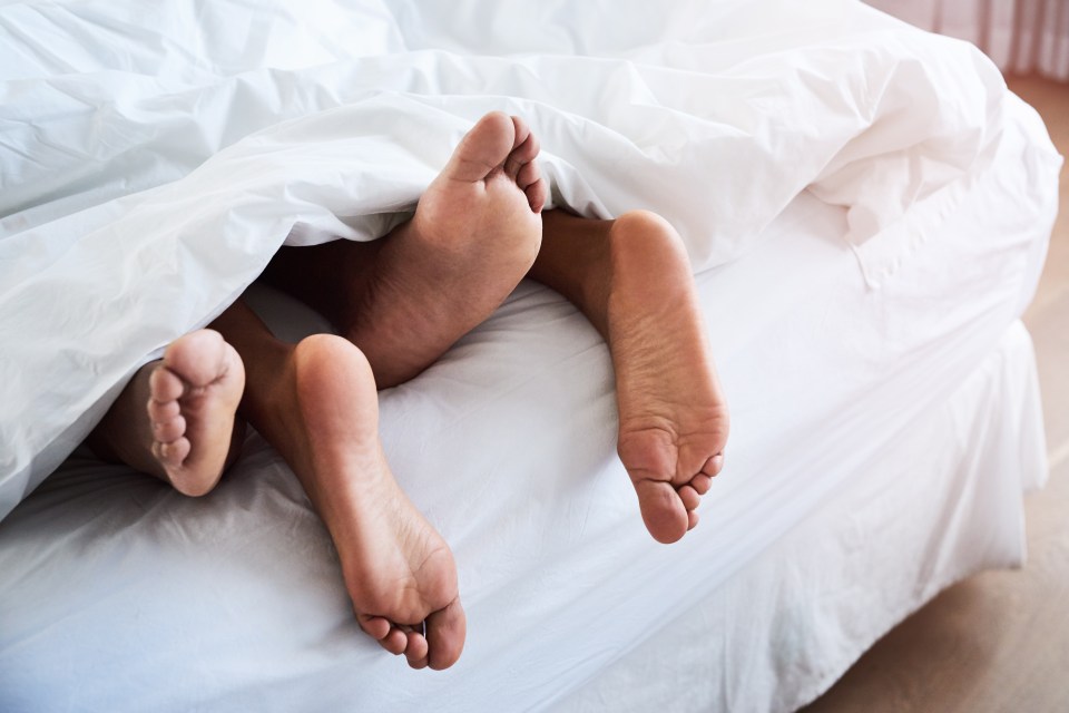 Couple's feet under white sheets.