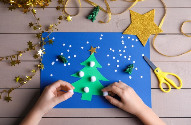 Little child making Christmas card at wooden table, top view; Shutterstock ID 1864530118; purchase_order: -; job: -; client: -; other: -