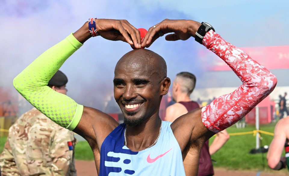 Sir Mo Farah making a heart shape with his hands above his head after a race.