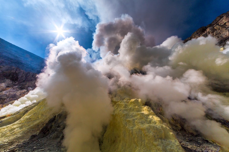 Steep slopes of the Ijen volcano crater are covered in yellow solidified sulphur