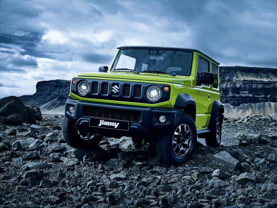 Green Suzuki Jimny driving on rocky terrain.