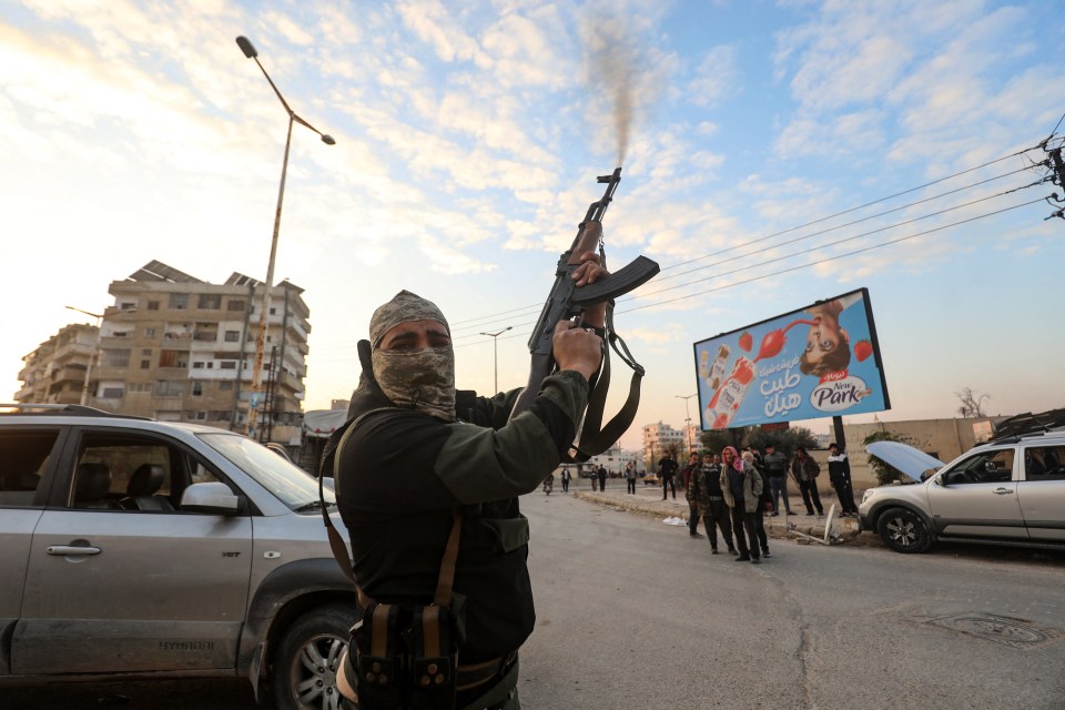 A Syrian anti government fighter fires his rifle into the air in the streets of the west-central city of Hama