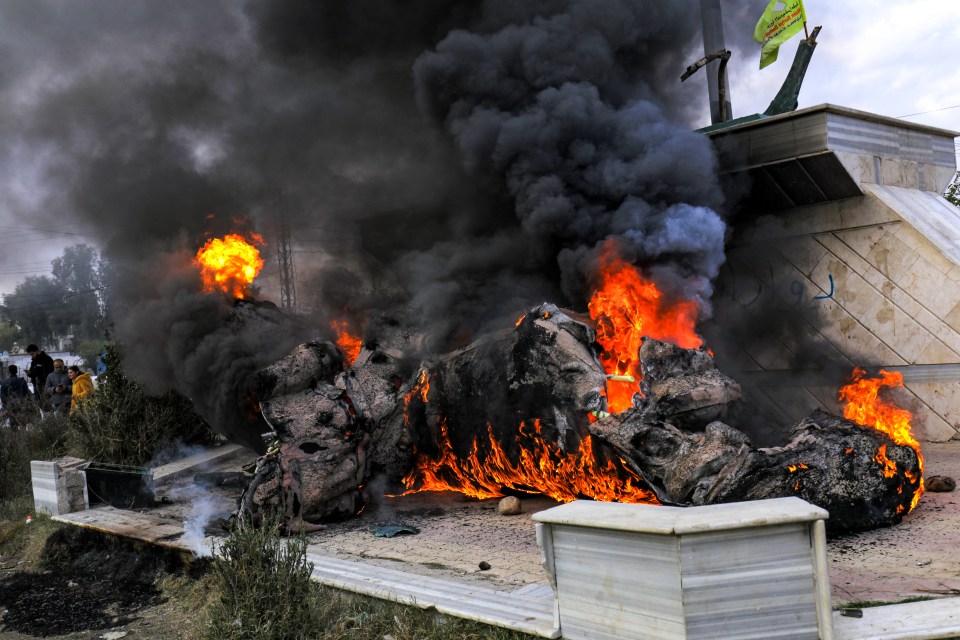 Syrian Kurds stand next to the destroyed statue of Basel al-Assad