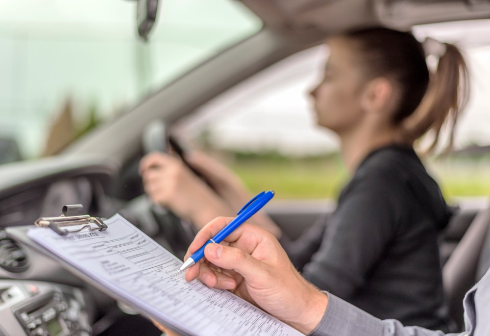 Driving instructor taking notes during a teenage girl's driving lesson.