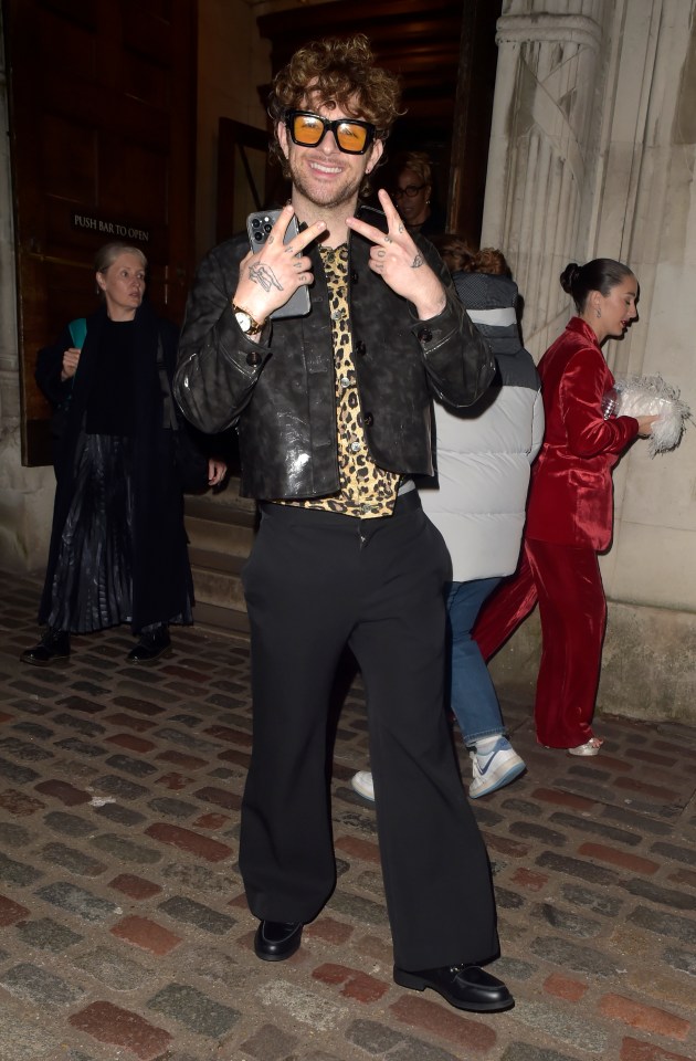 Tom Grennan poses in a leopard print top and tinted sunglasses