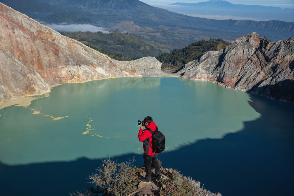 Traveler taking a photography on the cliff of Kawah Ijen volcano, Indonesia