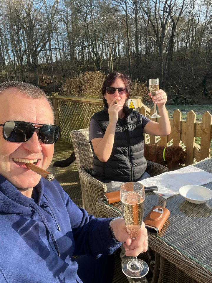 Wayne Mardle and his wife enjoying champagne and cigars outdoors.