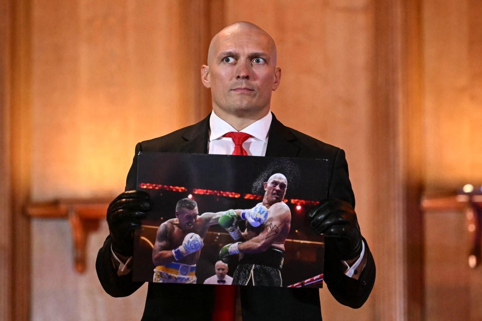 Oleksandr Usyk holding a signed photo of Tyson Fury.