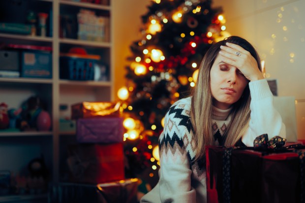 Depressed woman sitting by a Christmas tree.