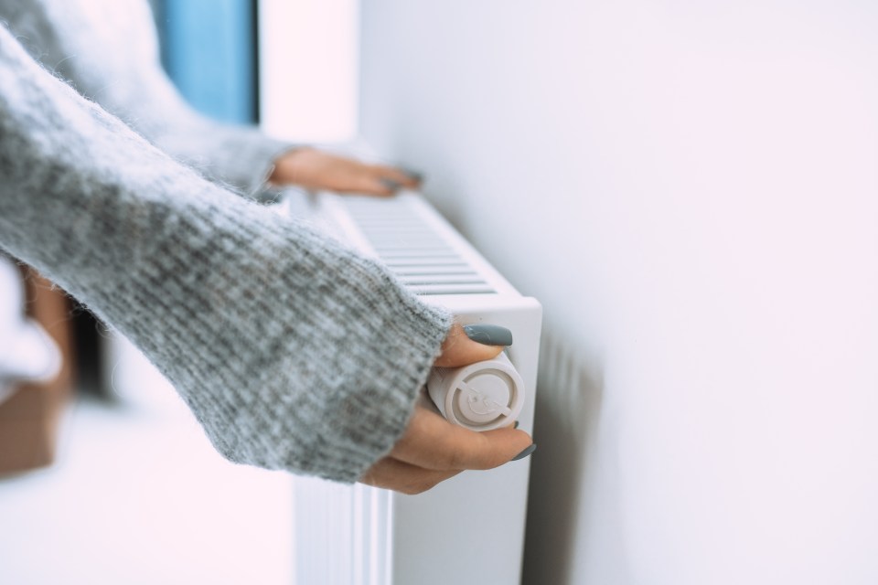 Hands adjusting a radiator thermostat.