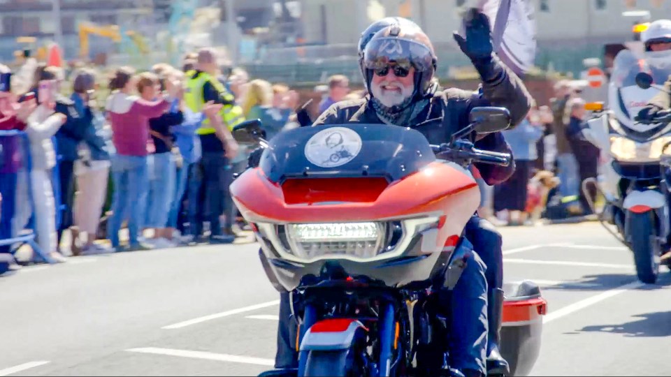 Si King waving from a motorcycle at a Dave Day event.