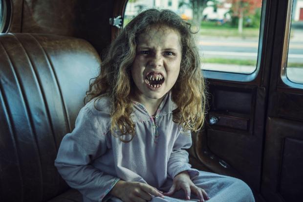 Darby Camp as a demonic child in a vintage car from the TV show NOS4A2.