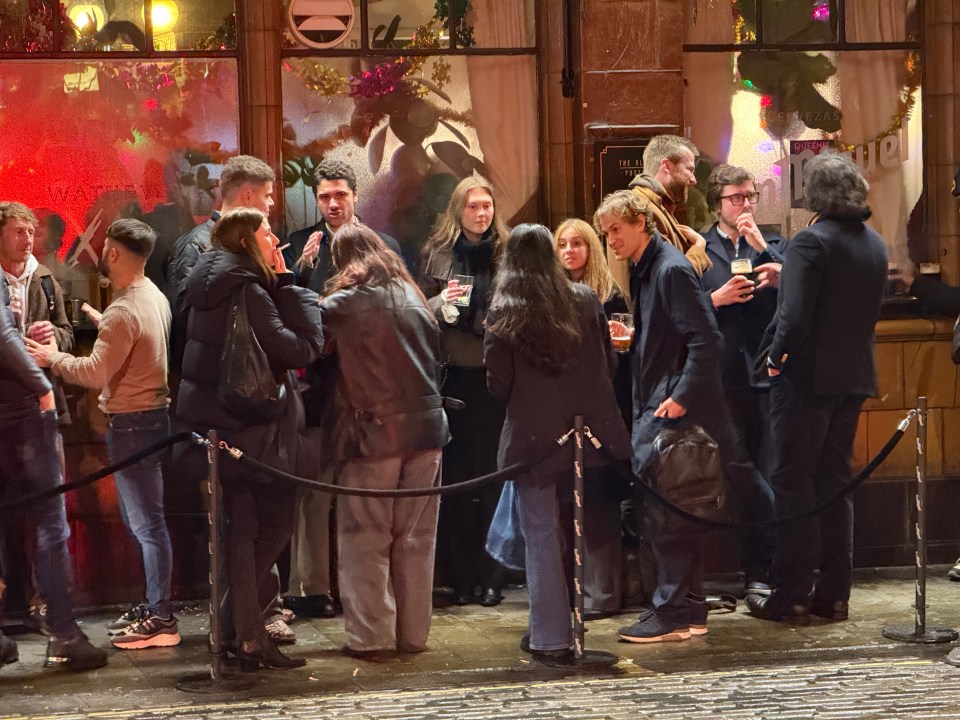 Still wearing office gear, boozers huddled in the smoking area of a bar in Soho