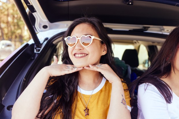 Woman wearing heart-shaped sunglasses in a car.