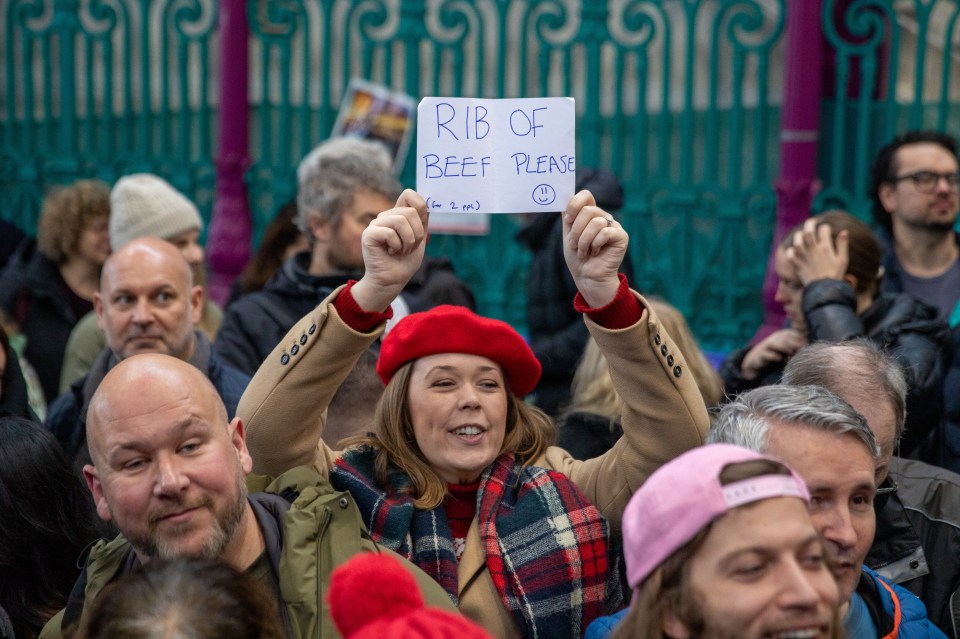 Woman holds sign requesting rib of beef at a meat auction.