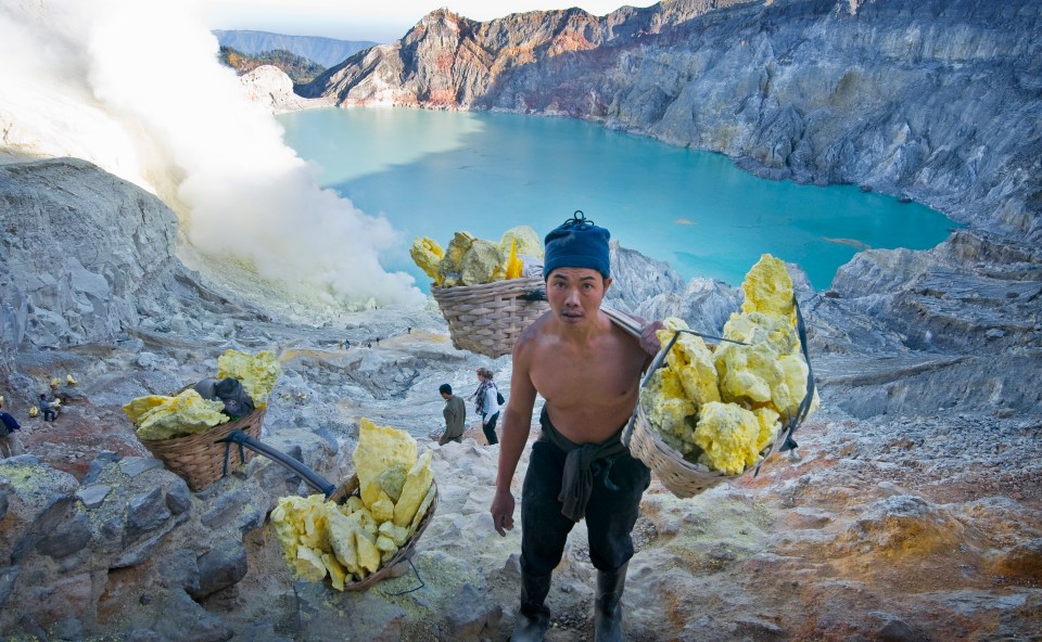 A worker carries sulphur blocks without wearing any face mask