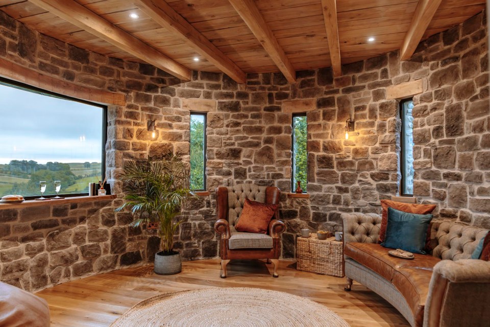 Bracken Tower interior: stone walls, wood beams, leather furniture, and a view.