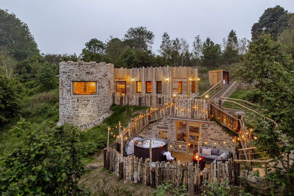 Bracken Tower, a stone and wood structure with a hot tub and fire pit, nestled in a wooded area.