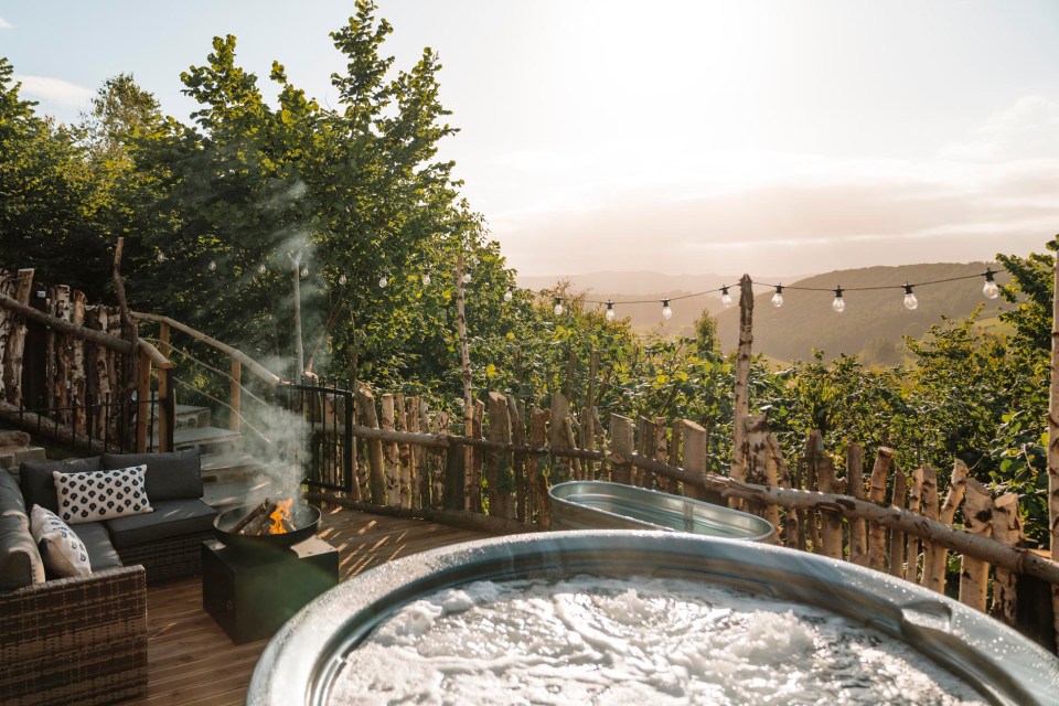 Hot tub and fire pit on a deck overlooking a valley.