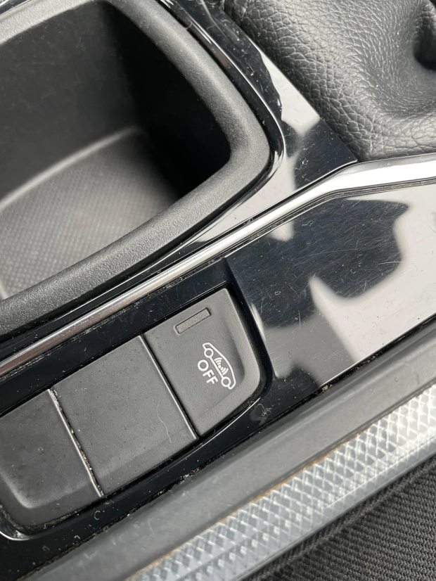 Close-up of a car's center console showing an &quot;OFF&quot; button with a car icon, indicating a vehicle feature's off setting.